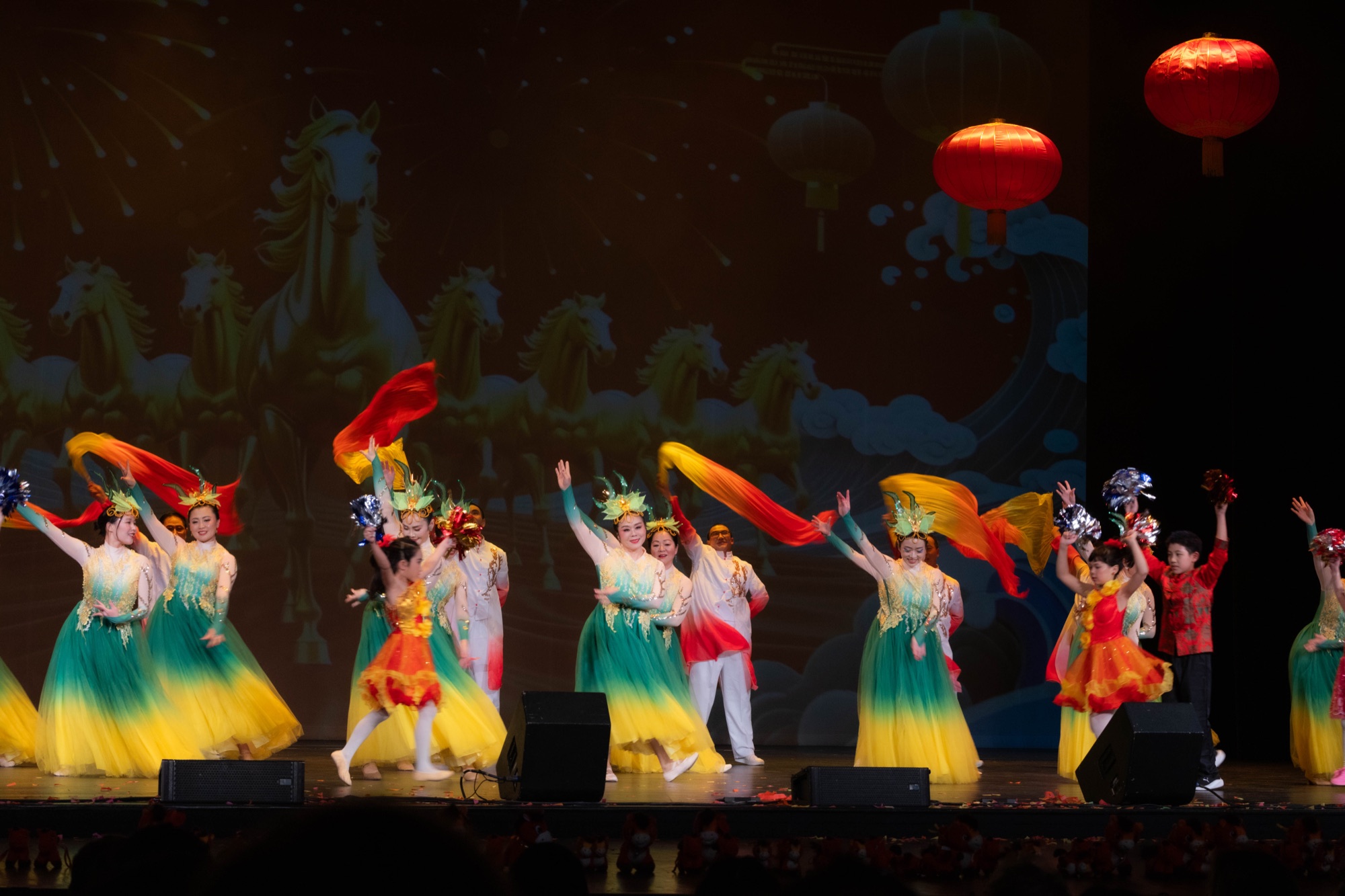 A group dance under theater stage lighting